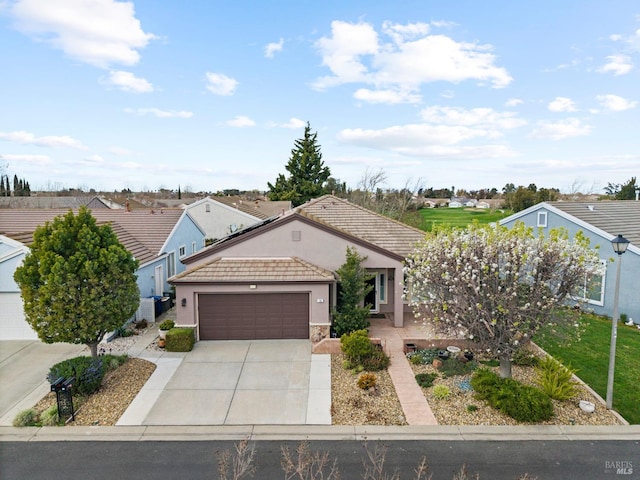 view of front facade with driveway, an attached garage, a tiled roof, and stucco siding