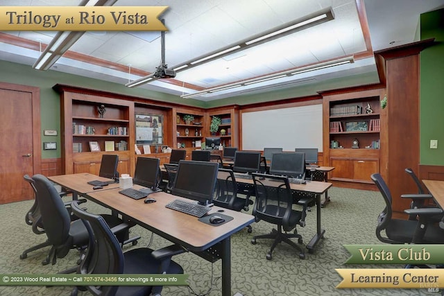 carpeted home office featuring a wainscoted wall and built in shelves