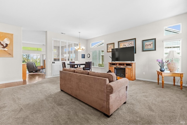 carpeted living room featuring baseboards, a fireplace, and a notable chandelier