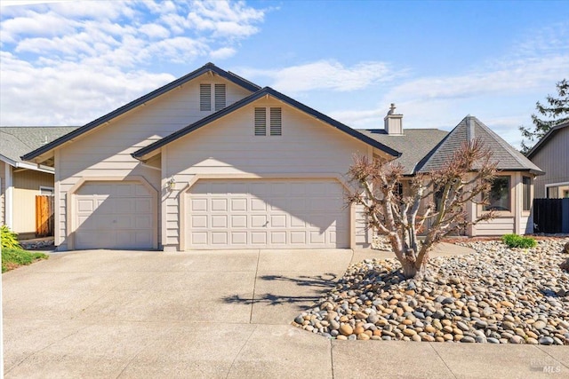 view of front of property with concrete driveway, a chimney, and a garage