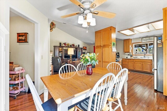 dining room with vaulted ceiling, a ceiling fan, and hardwood / wood-style flooring