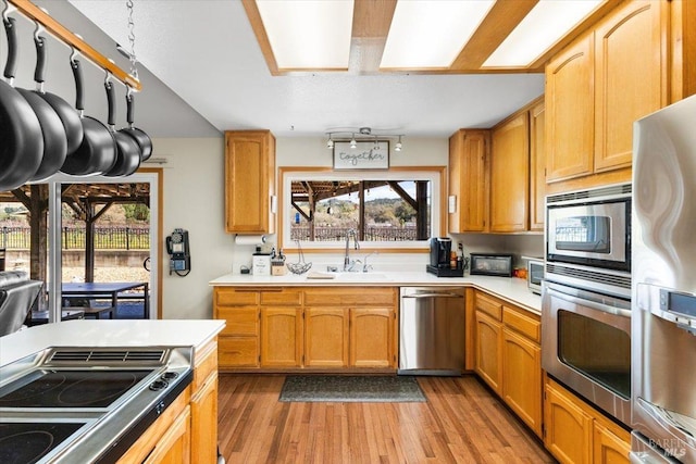 kitchen featuring stainless steel appliances, a sink, a wealth of natural light, light wood-style floors, and light countertops