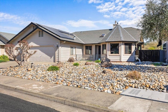 view of front of property featuring a garage, fence, a chimney, and solar panels