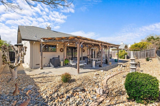 back of house with a fenced backyard, a pergola, a chimney, a shingled roof, and a patio