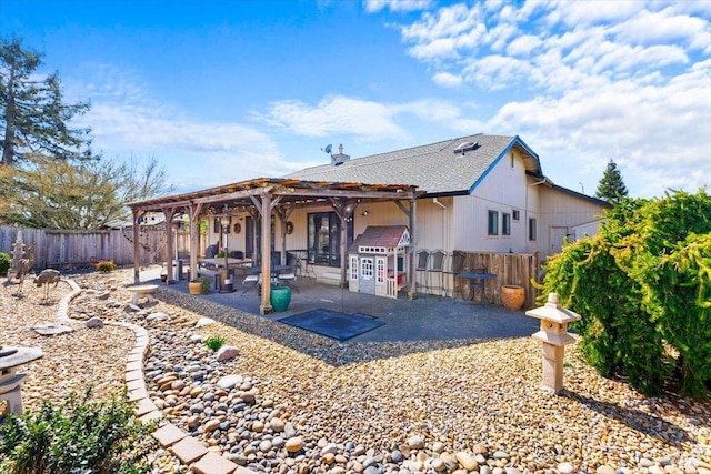 rear view of property with a pergola, a patio, a fenced backyard, and a shingled roof