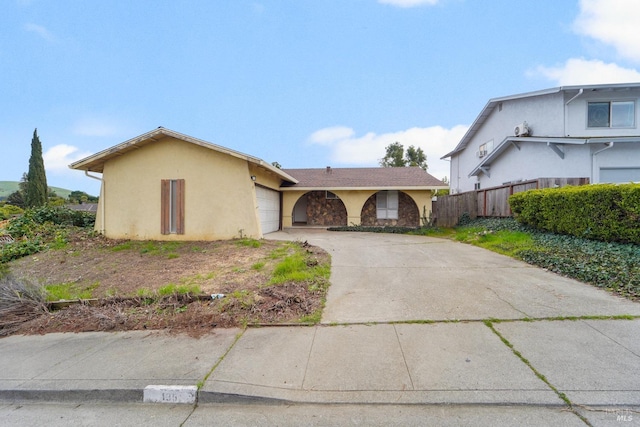 view of front facade featuring a garage, concrete driveway, fence, and stucco siding