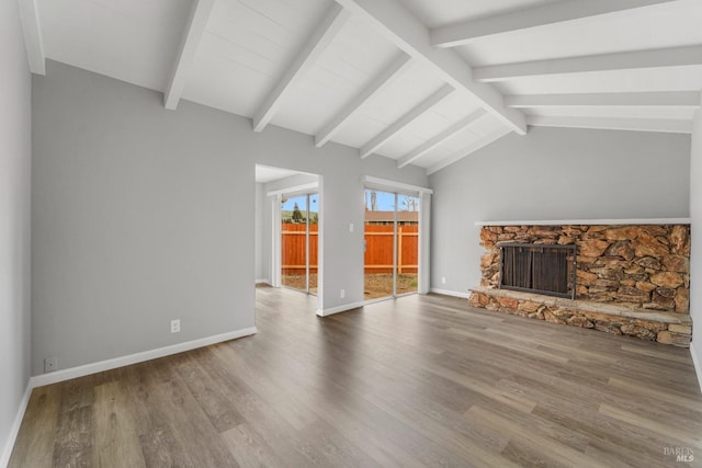 unfurnished living room with vaulted ceiling with beams, a fireplace, baseboards, and wood finished floors