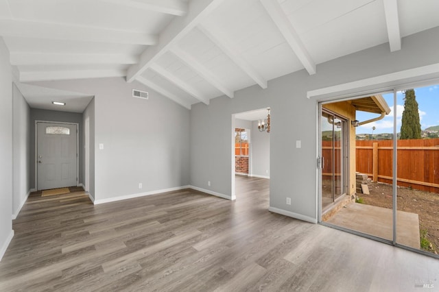 unfurnished living room featuring lofted ceiling with beams, wood finished floors, visible vents, baseboards, and an inviting chandelier