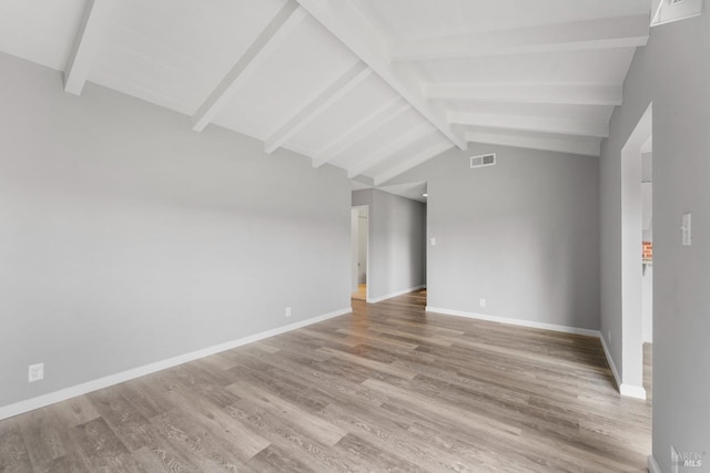 unfurnished room featuring lofted ceiling with beams, wood finished floors, visible vents, and baseboards