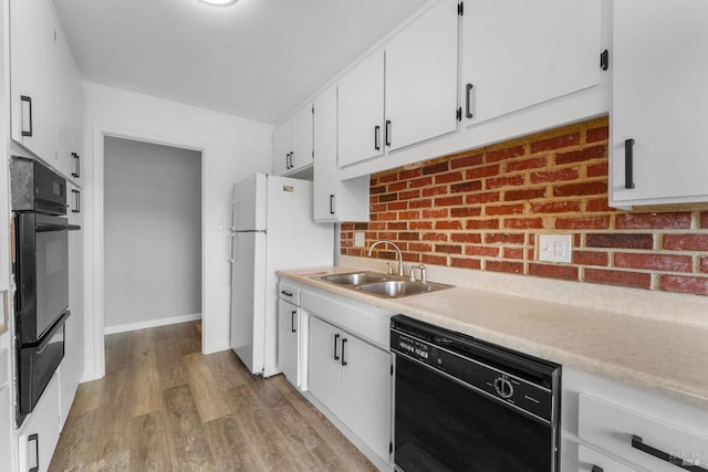 kitchen with wood finished floors, a sink, black dishwasher, light countertops, and a warming drawer