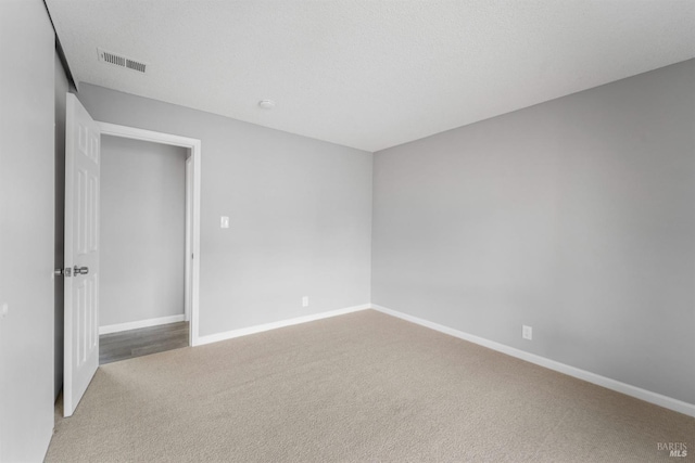 carpeted empty room featuring baseboards and visible vents