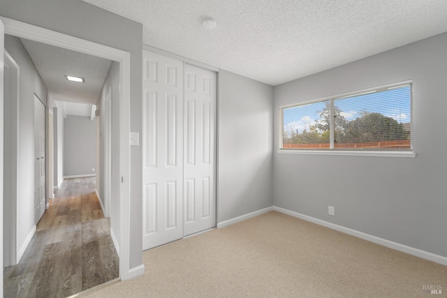 unfurnished bedroom with a closet, a textured ceiling, and baseboards