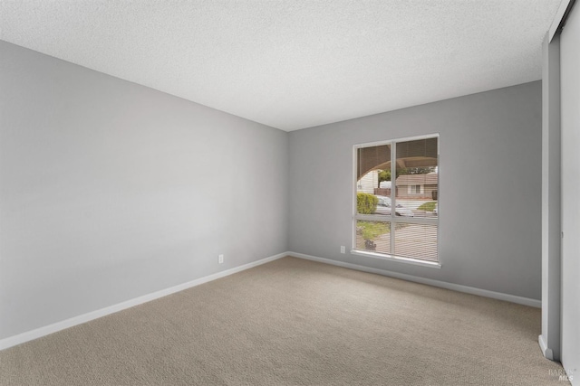 empty room with a textured ceiling, carpet, and baseboards