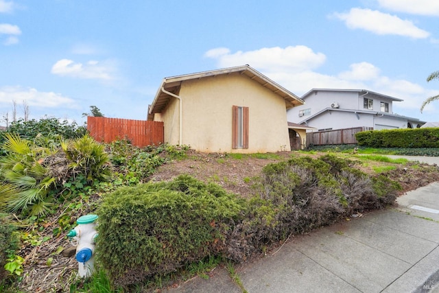 view of side of home with fence and stucco siding