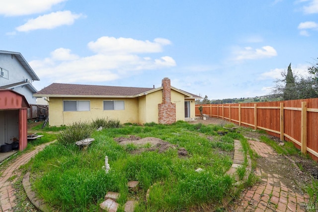 view of yard featuring an outbuilding, a fenced backyard, and a shed