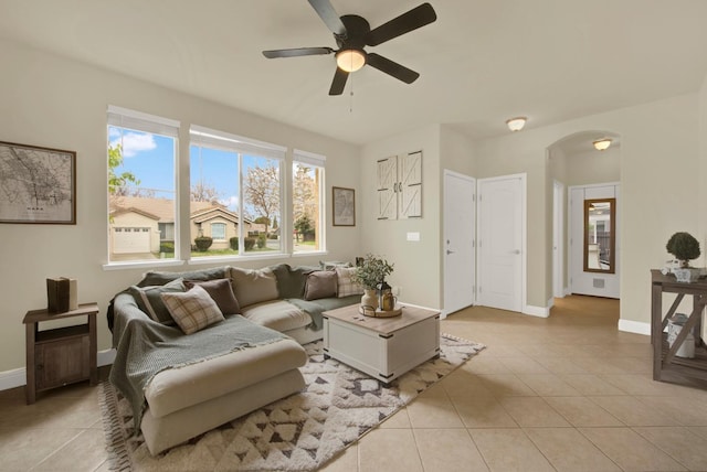 living area featuring arched walkways, light tile patterned floors, and baseboards