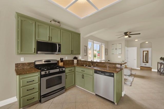 kitchen with arched walkways, appliances with stainless steel finishes, green cabinets, and a sink