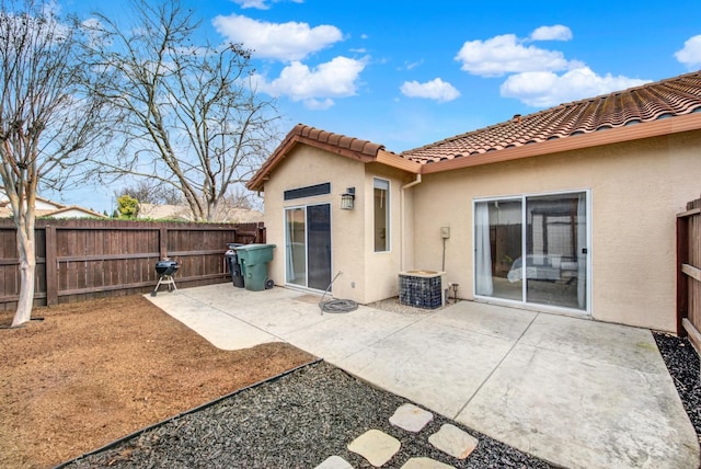 back of property with a tiled roof, a fenced backyard, a patio, and stucco siding