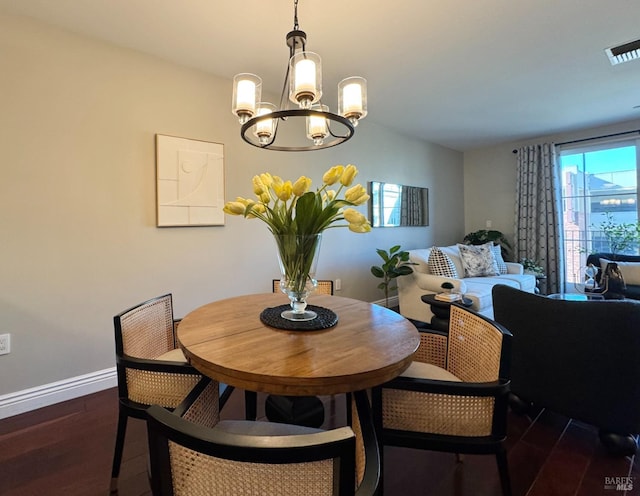 dining area featuring baseboards, visible vents, dark wood finished floors, and a chandelier