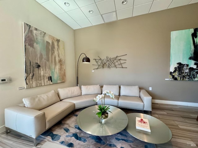 living room with baseboards, a drop ceiling, and wood finished floors