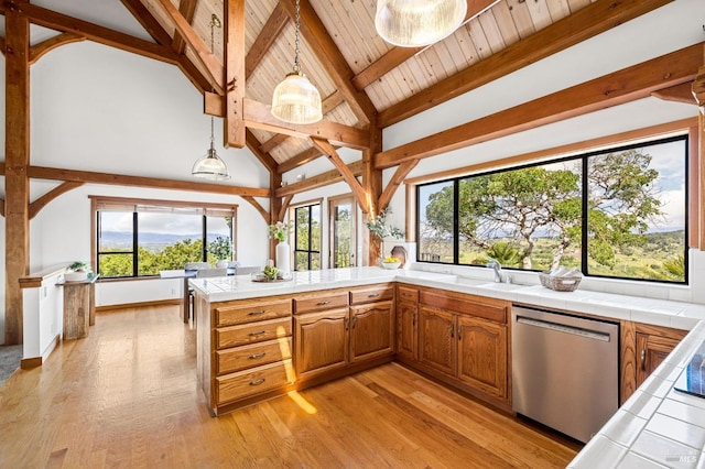 kitchen featuring tile counters, light wood-style floors, beamed ceiling, and stainless steel dishwasher