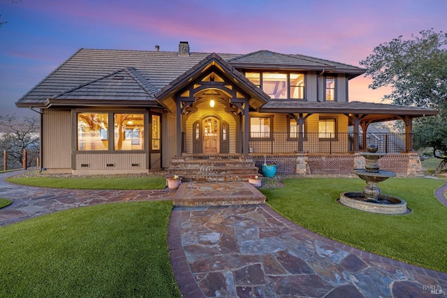 view of front of property with a porch, a tile roof, crawl space, a lawn, and a chimney