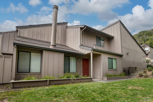 rear view of property with a lawn, board and batten siding, and a shingled roof