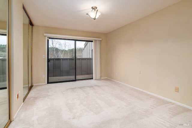 spare room with baseboards and light colored carpet