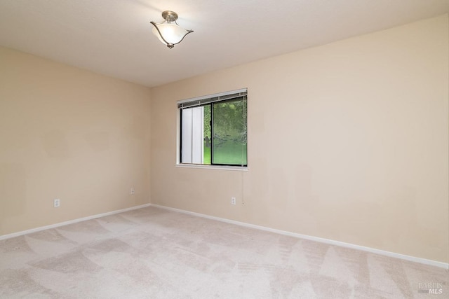 unfurnished room with light carpet and baseboards