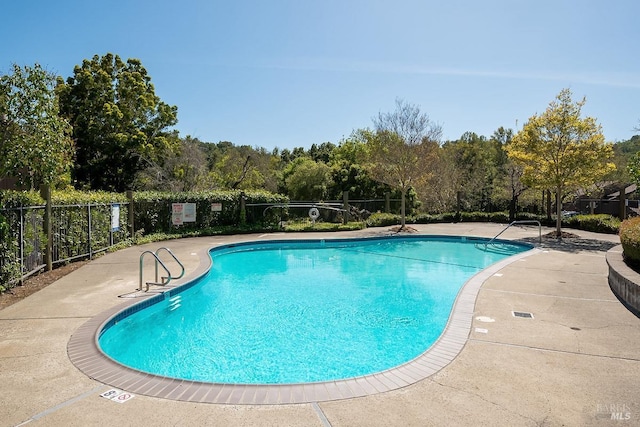 community pool with a patio area and fence