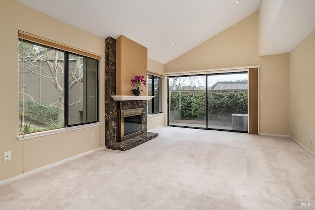 unfurnished living room featuring high vaulted ceiling, carpet flooring, baseboards, and a premium fireplace