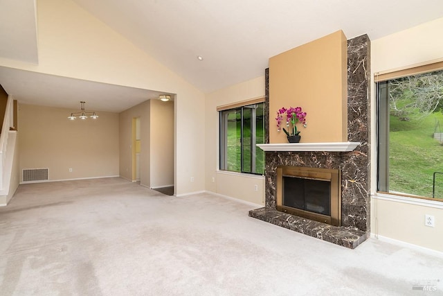 unfurnished living room with a high end fireplace, visible vents, a chandelier, lofted ceiling, and carpet floors