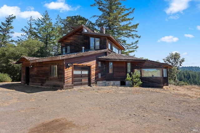 view of front of property featuring driveway, a chimney, and an attached garage