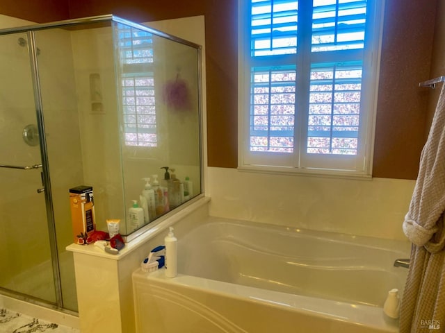 bathroom featuring a garden tub and a shower stall