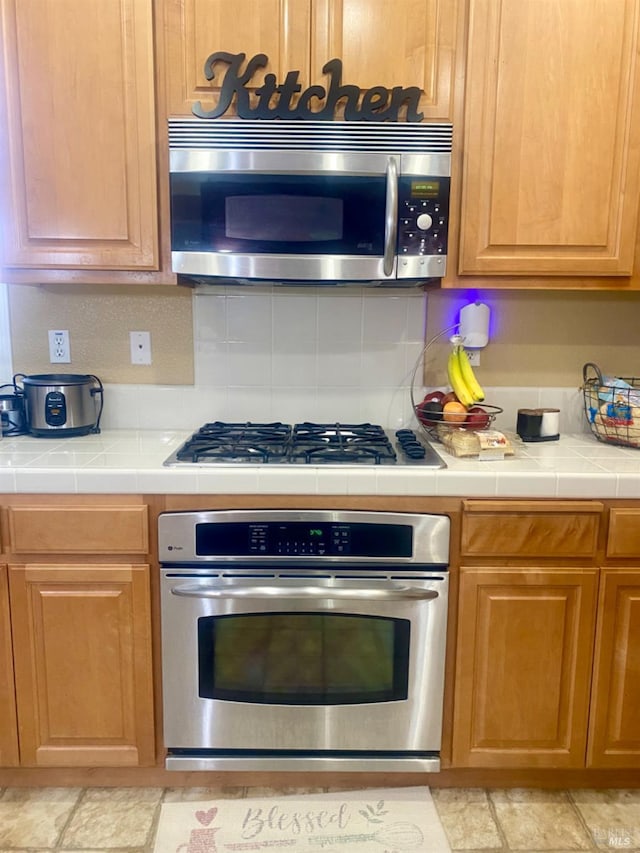 kitchen with decorative backsplash, stainless steel appliances, and tile counters