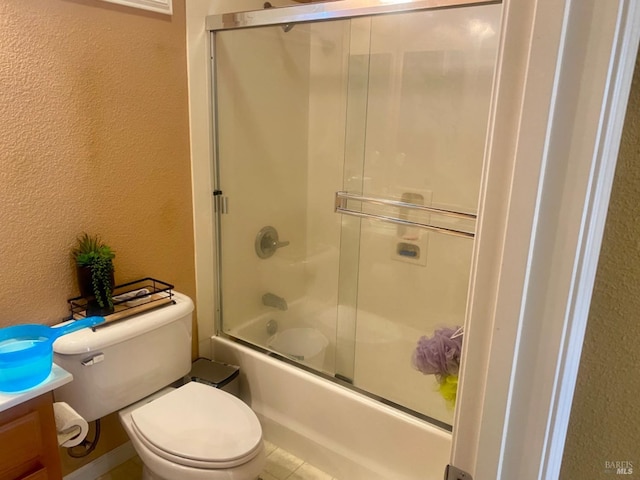 full bath featuring vanity, toilet, shower / bath combination with glass door, and a textured wall