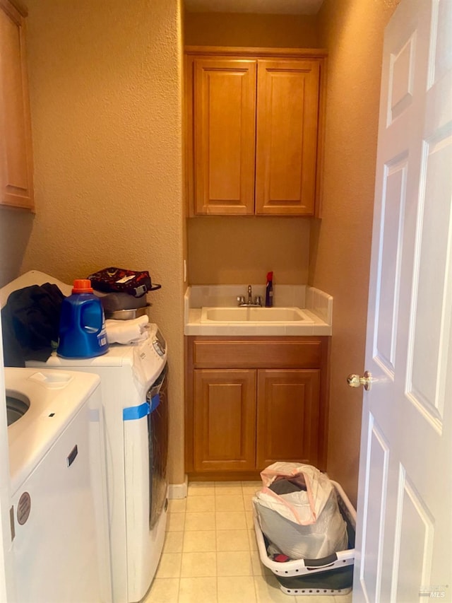 clothes washing area with light tile patterned floors, cabinet space, independent washer and dryer, and a sink