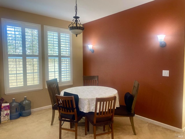 dining area featuring baseboards and light carpet