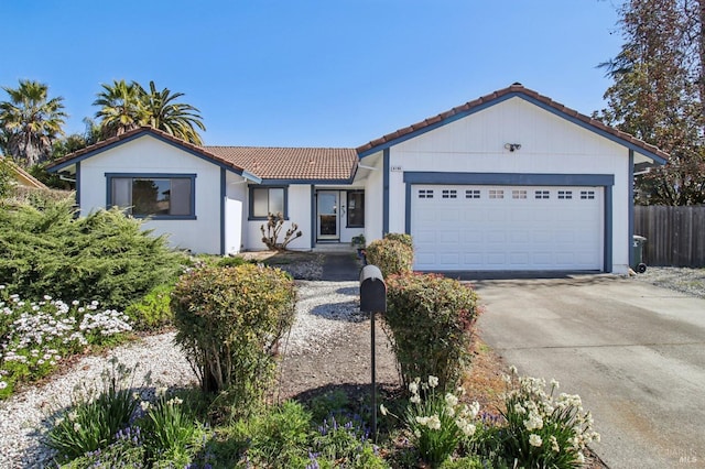 view of front of house featuring a garage, concrete driveway, a tile roof, and fence