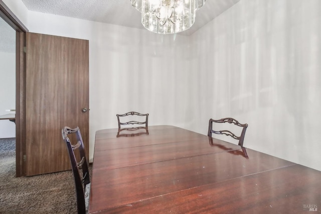 carpeted dining room featuring an inviting chandelier and a textured ceiling