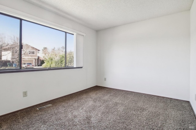 spare room featuring visible vents, carpet floors, and a textured ceiling