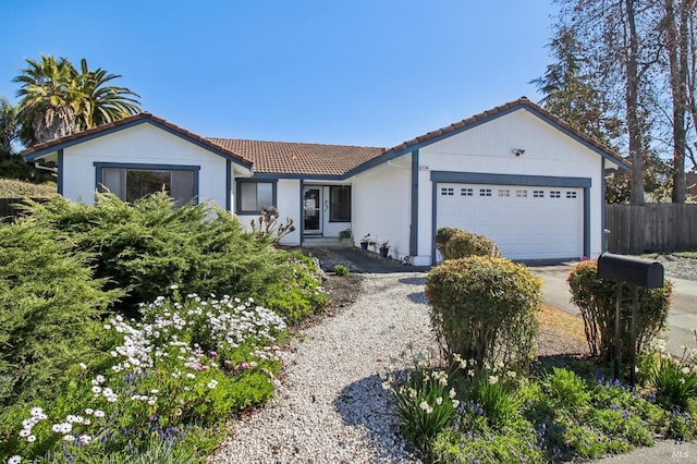 ranch-style home featuring a tile roof, an attached garage, fence, and driveway