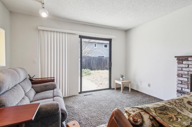 carpeted living area featuring visible vents, a textured ceiling, and a fireplace with raised hearth