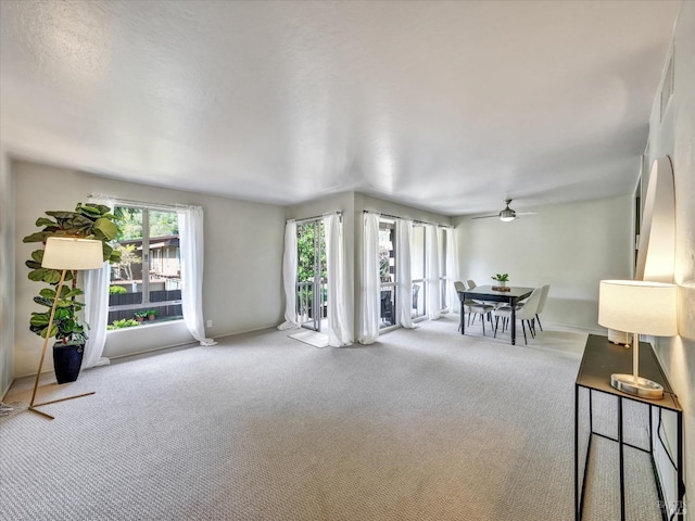 living room with baseboards, a ceiling fan, and carpet flooring