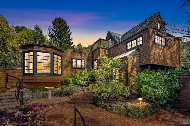 back of property at dusk with a balcony