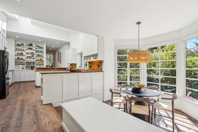 kitchen with open shelves, white cabinets, and wood finished floors