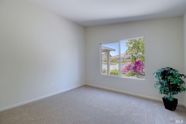 carpeted spare room featuring baseboards