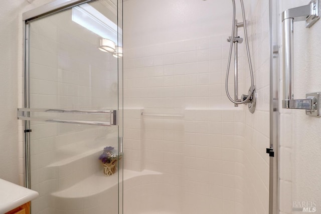 bathroom featuring a stall shower, a textured wall, and vanity