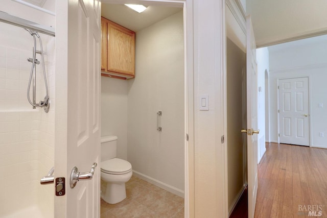 bathroom with walk in shower, toilet, and baseboards