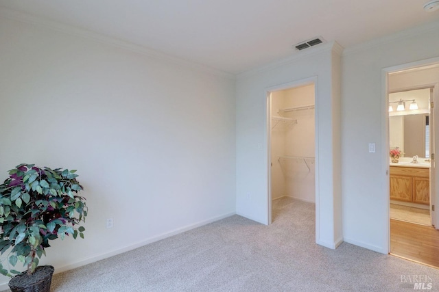 unfurnished bedroom with light colored carpet, visible vents, crown molding, and baseboards